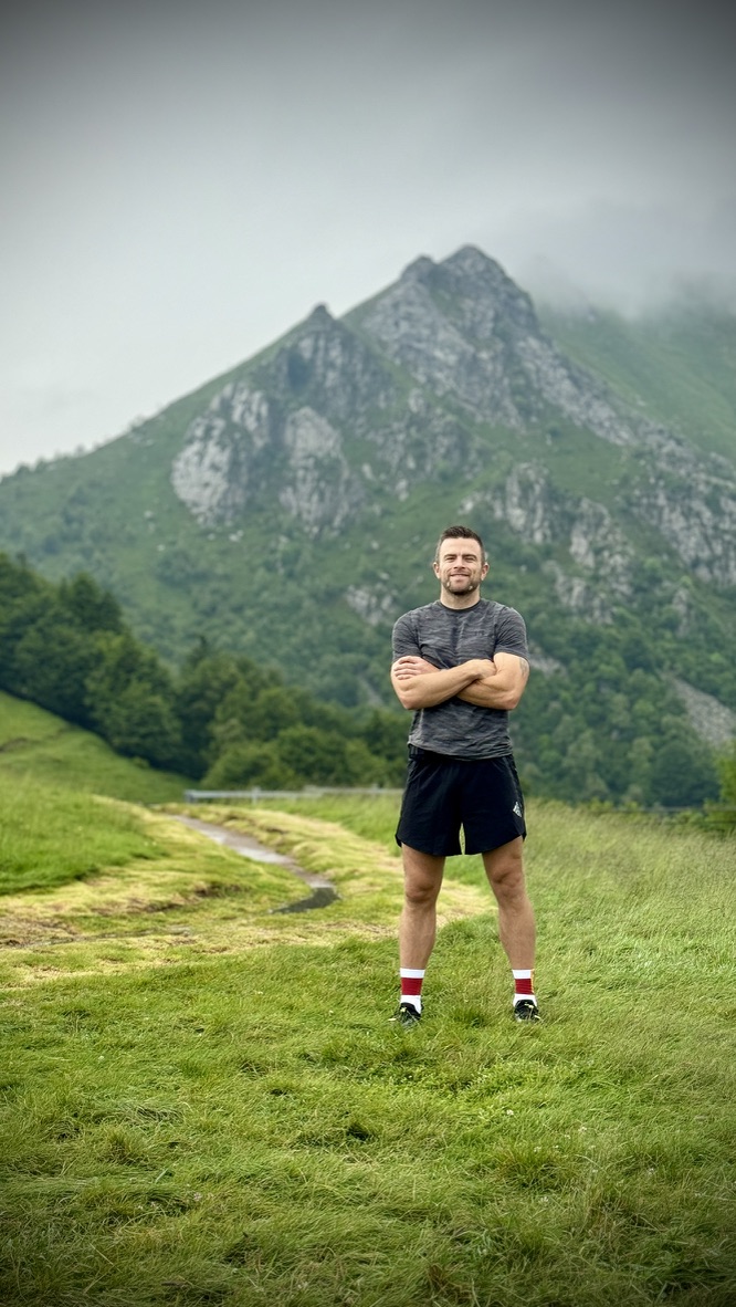 Patrik Widell står i träningskläder framför gröna berg.