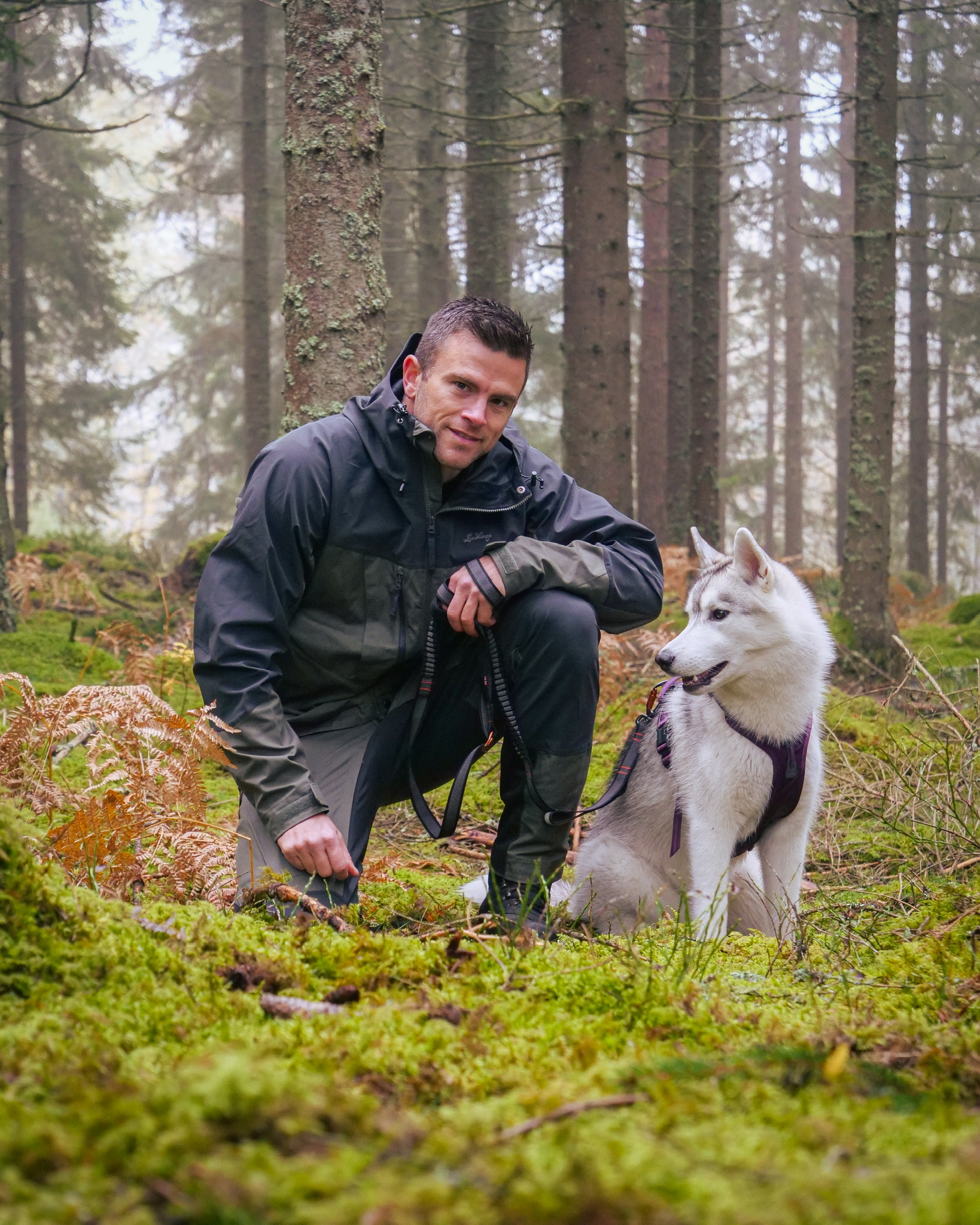 Patrik Widell sitter i skogen med en hund under en outdoor-aktivitet.