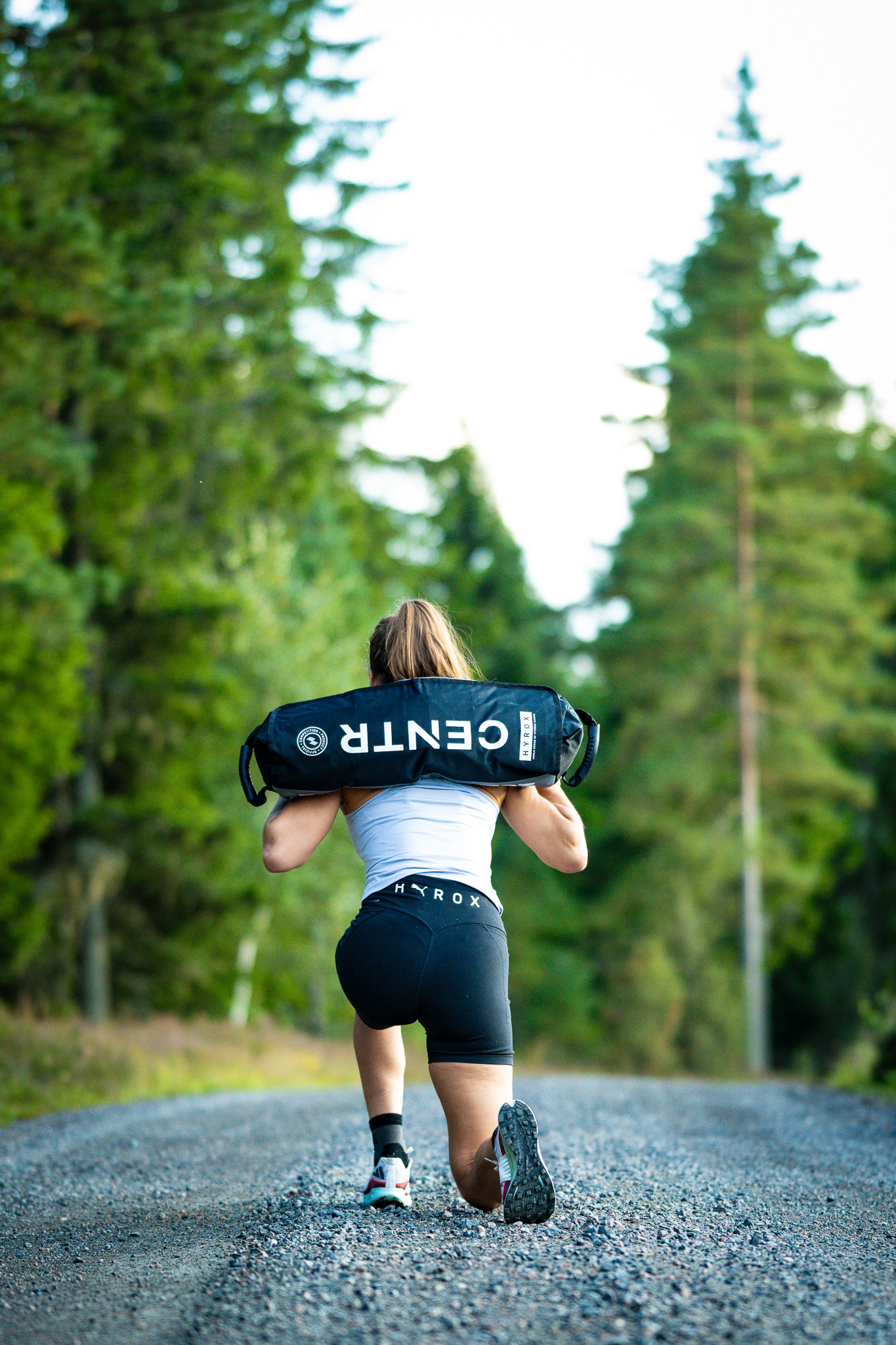 Person går med sandbag på skogsväg.