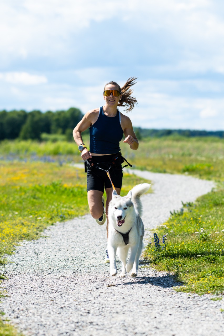 Löpare springer med hund i ett öppet landskap.